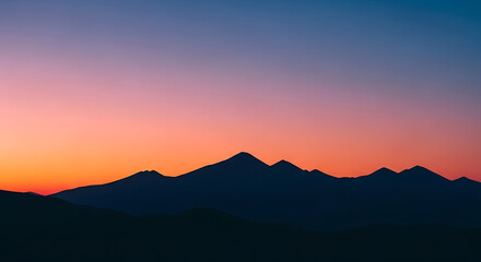 Obraz premium A beautiful evening view of the sun setting over misty mountain peaks as golden light glows across the horizon and clouds drift above the forest hills at dusk