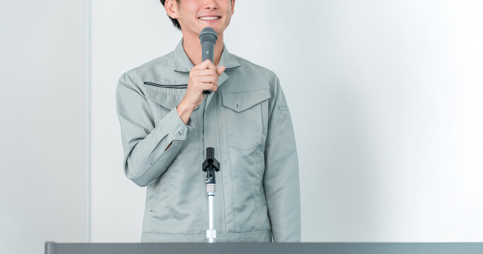 Male staff members in work clothes, such as manufacturing workers, factory workers, and engineers, acting as moderators or presenters at meetings, training sessions, and seminars.