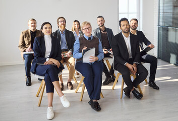 Obraz premium People team meeting in office with coach. Leader guides a group in training as audience notes ideas in a bright workspace for onboarding and seminar themes. Concept of teamwork and leadership.