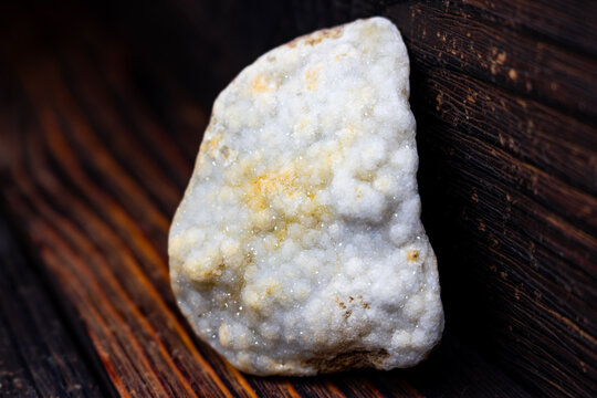 Glistening raw quartz druzy featuring countless tiny sparkling crystals, resting on a rustic dark wood surface, showcasing natural mineral beauty and texture
