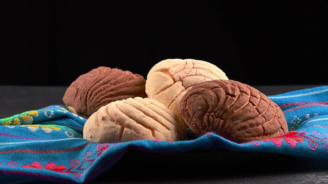 Mexican conchas with vanilla and chocolate flavor on a blue cloth napkin, dark background