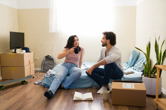 Man and woman communicating, planning their new beginnings in their empty, minimalist apartment with essential belongings