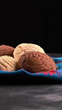 Mexican food, conchas with vanilla and chocolate flavor on a blue cloth napkin, dark background