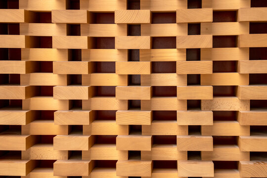 Abstract architectural wood wall with a repetitive geometric pattern of blocks. Minimalist timber texture with rhythmic highlights and shadows for modern interior design and background use.