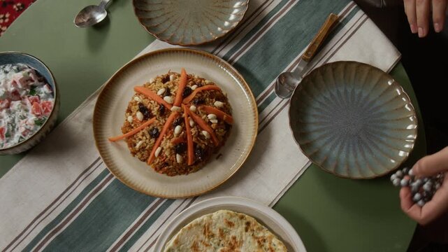 Top view close up shot of unrecognizable Muslim couple eating traditional meal at home with focus on maklouba dish and flatbread, copy space