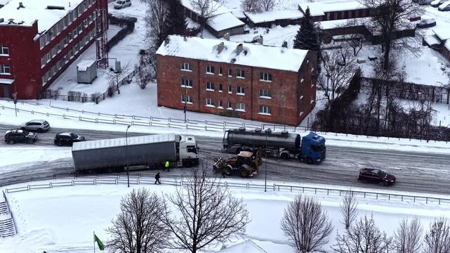 Truck losing traction on icy road uphill causing winter traffic disruption, aerial view