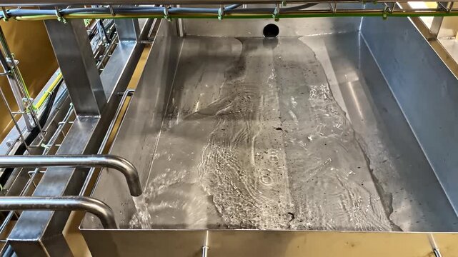 The clean stainless steel tank and pipes in a dairy plant are rinsed.