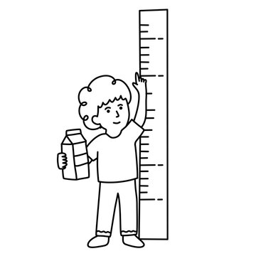 Young boy measuring his height next to wall chart holding milk carton