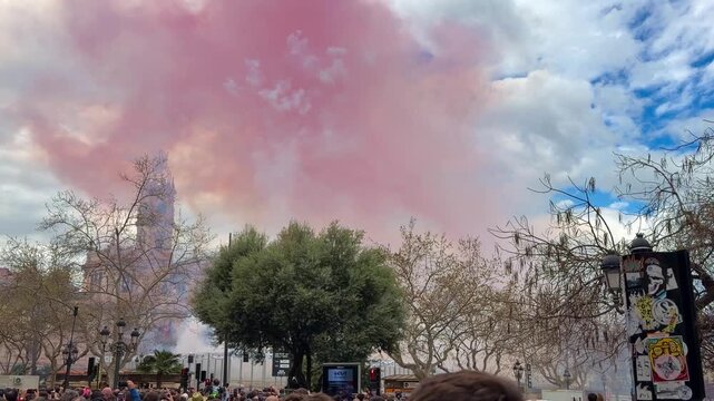 Landscape view of Plaza del Ayuntamiento, Valencia, experiencing Masclet&agrave; the vibrant traditional Fallas festival under a bright sky with historic buildings surrounding the square