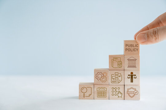 Public Policy, Governance, Law, Regulation, Government, Legislation, Strategy concept with businessman stacking wooden blocks to represent building a social framework for society.
