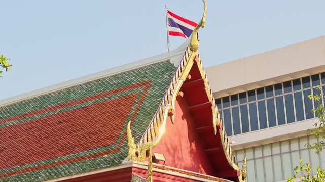 Closeup of ornate Thai temple roof with glass building background
