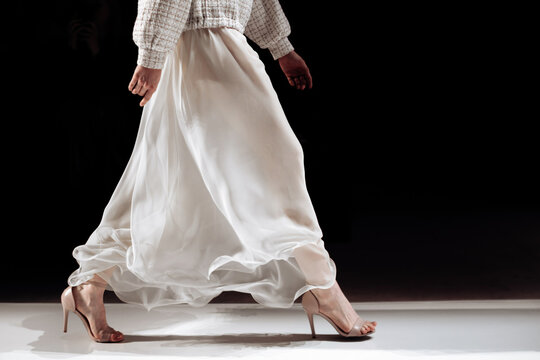 Chic satin long white skirt and beige high heels, woman's elegant outfit on black background