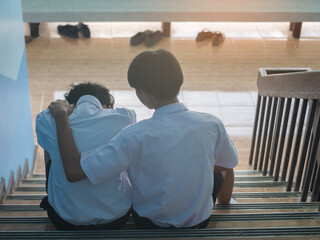 High School Student Comforting Sad Friend on Staircase at School