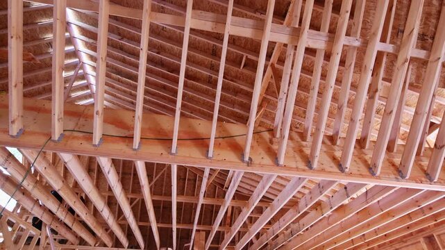 Natural light fills newly constructed attic with wooden beams rafters, ongoing renovation process.