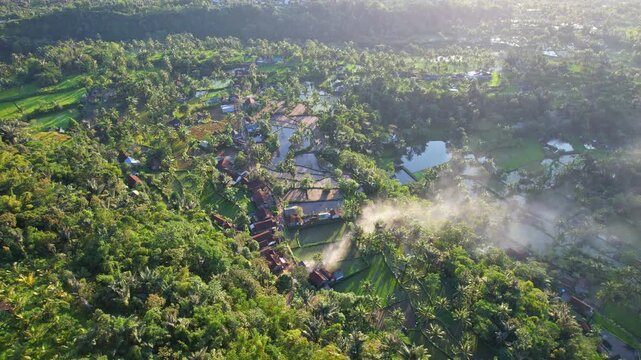 Aerial drone footage of a local village nearby Galunggung volcano mountain, at early sunrise, smokes, near Citiis hot spring area, wild forest around, in Tasikmalaya regency, Java island, Indonesia