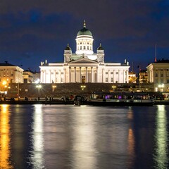 Fototapeta premium A serene nighttime scene of a large white building with a green dome by a body of water