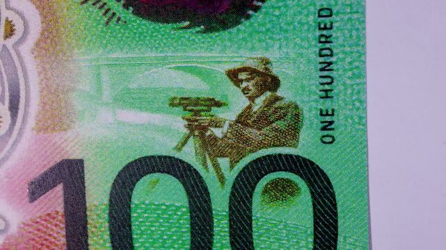 Fast-paced stop motion sequence of Australian 100 dollar polymer banknotes. Extreme macro photography montage highlighting portraits, currency details, and security features.
