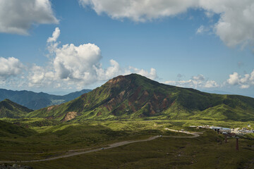 Obraz premium Vast volcanic landscape with green mountains, crater terrain and dramatic summer clouds