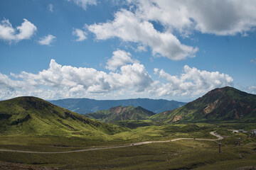 Fototapeta premium Vast volcanic landscape with green mountains, crater terrain and dramatic summer clouds