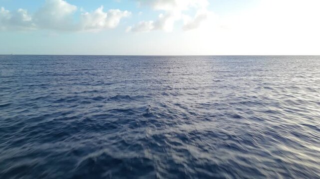 Aerial drone shot of calm tropical sea with glassy reflections and heavy cloud cover creating moody scene