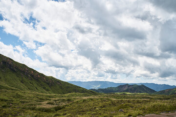 Fototapeta premium Vast volcanic landscape with green mountains, crater terrain and dramatic summer clouds