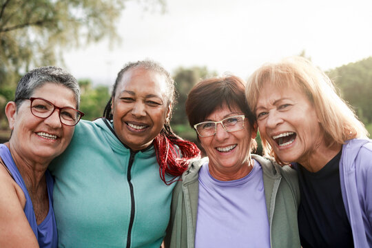 Diverse elderly people having fun hugging each other outside after sport training