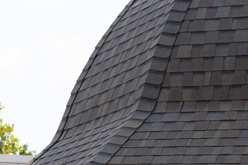 roof shingle background and texture. dark asphalt tiles on the edge of curve roof.