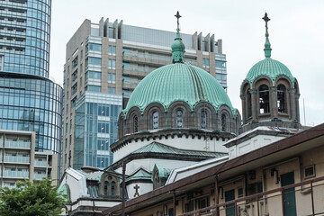 Naklejka premium Historic domed church facade amid modern office towers in city center