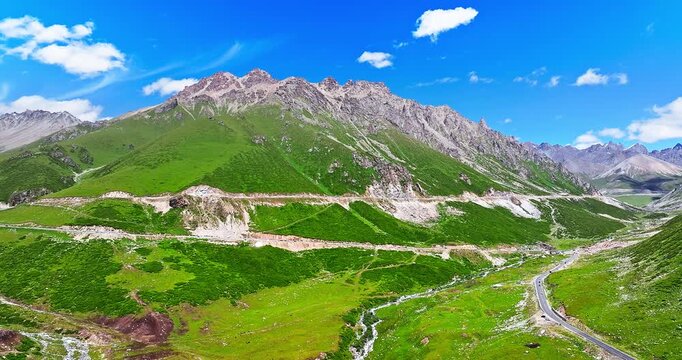 Aerial view of a winding road on steep green mountain slopes, Xinjiang, China
