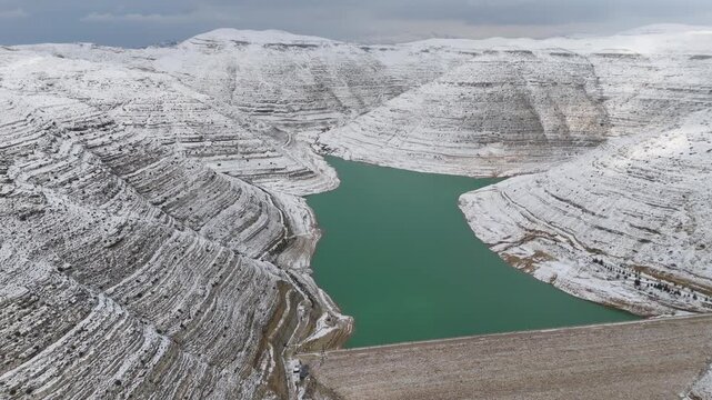 Beautiful contrast between turquoise water and snow-covered dam structure at Chabrouh Dam in winter.