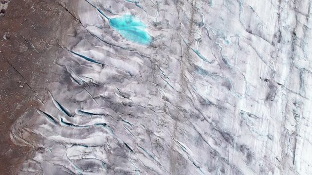 Aerial drone 4k close‑up of the Aletsch Glacier showing cracked ice, crevasses, and blue meltwater pools, highlighting glacier texture and visible effects of climate change in the Swiss Alps