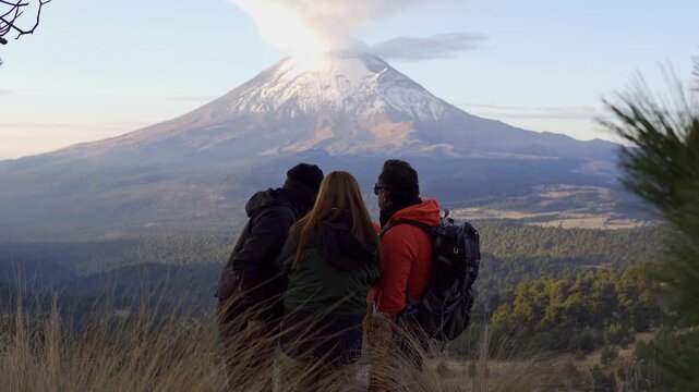 Three hikers taking a selfie with the popocatepetl volcano in mexico