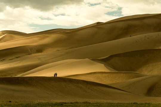 USA, Colorado, Great Sand Dune National Park.  A couple walking on the edge of a dune.   The dunes cover an area of about 30 sq mi (78 km2)