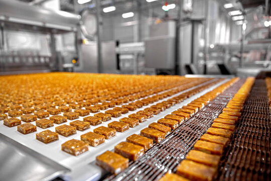 Caramel and nougat candies moving along an industrial assembly line in a food factory