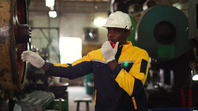 Professional industrial engineer communicating with walkie talkie during factory inspection