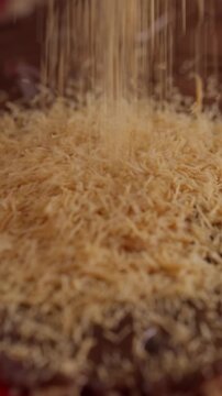 Slow motion close-up of kataifi pastry strands falling onto melted chocolate. Crispy shredded dough creating rich textured dessert surface. Food preparation and Middle Eastern dessert concept.