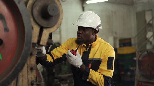 Professional industrial engineer communicating with walkie talkie during factory inspection