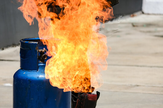 Close up of tank gas  fire burning from a blue gas cylinder tank concept of gas leak explosion, domestic fire accident, household safety hazard, and fire fighting demonstration or emergency training.