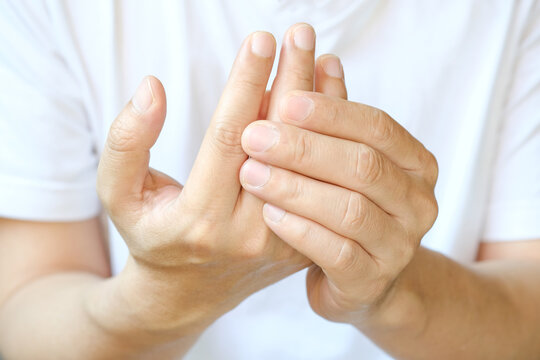 Man holding his hand suffering from finger joint pain or numbness; concept of arthritis, carpal tunnel syndrome, gout and trigger finger from work and office syndrome medical concept