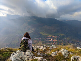 Naklejka premium Woman admires serene mountain view from rocky peak.