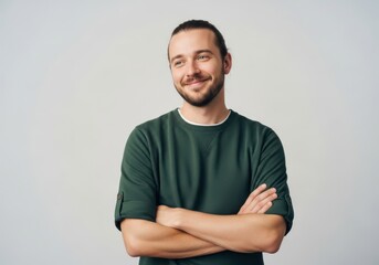 Fototapeta premium Confident young man with beard and top knot posing with crossed arms on white background