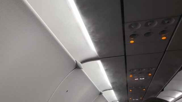 Cold air condensation mist coming from the overhead vents in an airplane cabin.