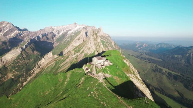 Aerial drone view of Schaeffler Hut alpine mountain lodge on a green ridge, Swiss Alps hiking destination, dramatic peaks, summer alpine landscape, scenic travel tourism footage Switzerland