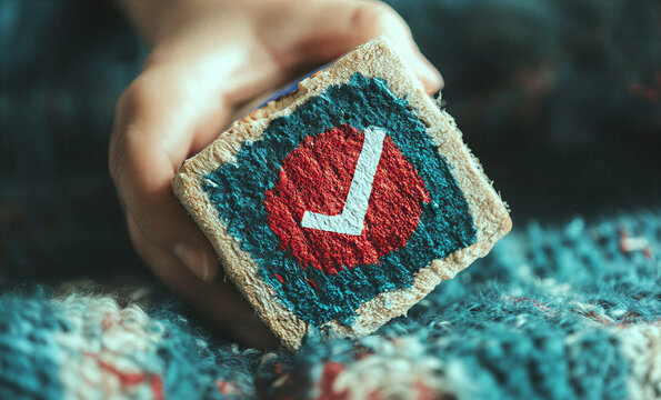 Hand holding embroidered bread with downvote symbol closeup