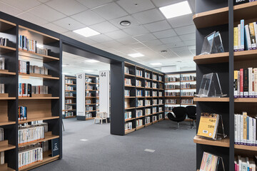 Wide library aisle with bookshelves in bright contemporary reading room © Namsun