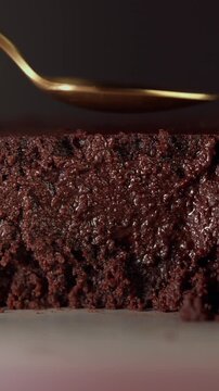 Macro shot of a spoon pressing into a soft chocolate brownie, revealing moist, rich and fudgy texture. Indulgent dessert experience.