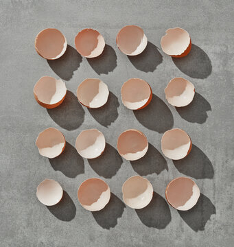 Eggshell halves arranged in grid with shadows on grey background