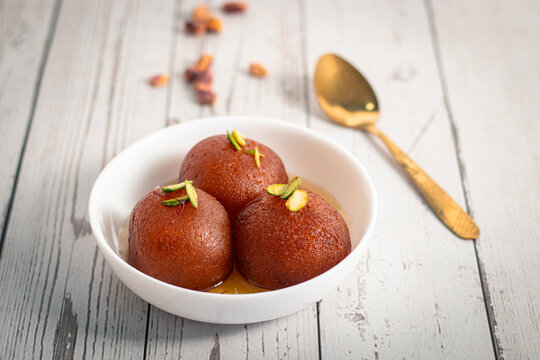 Soft juicy gulab jamun soaked sugar syrup garnished pistachio served in bowl traditional Indian dessert sweet festive delicious indulgent treat
