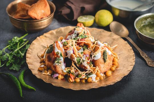 Samosa chaat topped yogurt chutney sev chickpeas onion Indian street food spicy tangy snack vibrant flavorful appetizer served fresh
