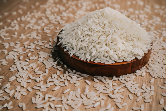 Close up of premium white rice grains pile a staple food in Asiaon with rustic wooden table background